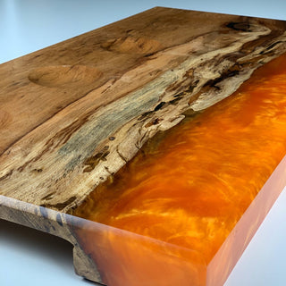 Hand-crafted wooden cutting board with one side made of orange epoxy resin