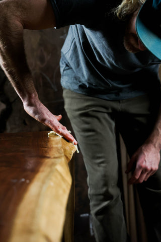 Man rubbing wax onto the edge of a table